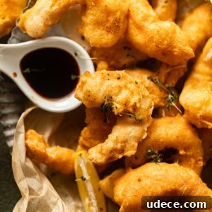 beer battered shrimp on a plate with malt vinegar in a small bowl.
