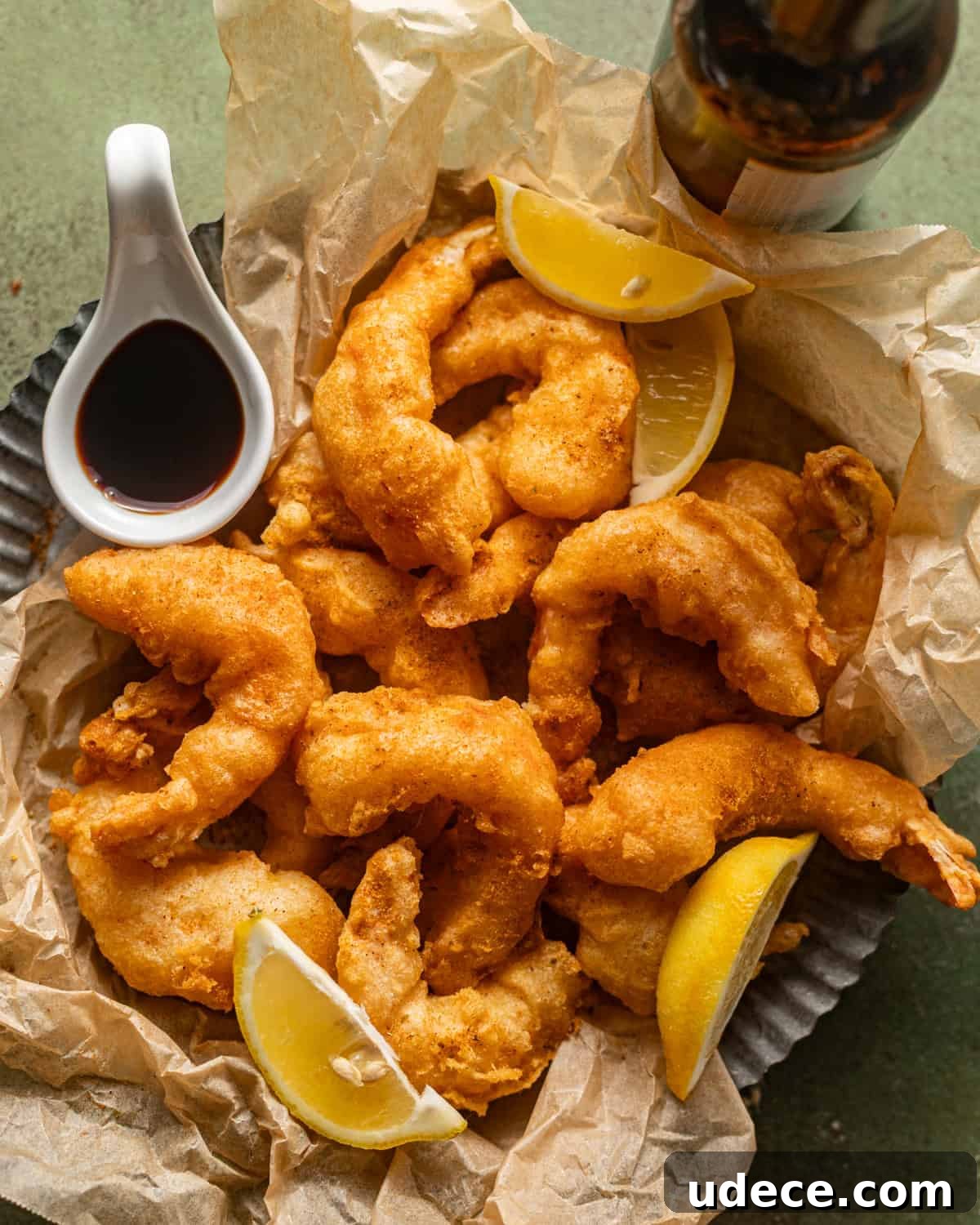 overhead photo of beer battered shrimp on a round plate with a small bowl of malt vinegar.