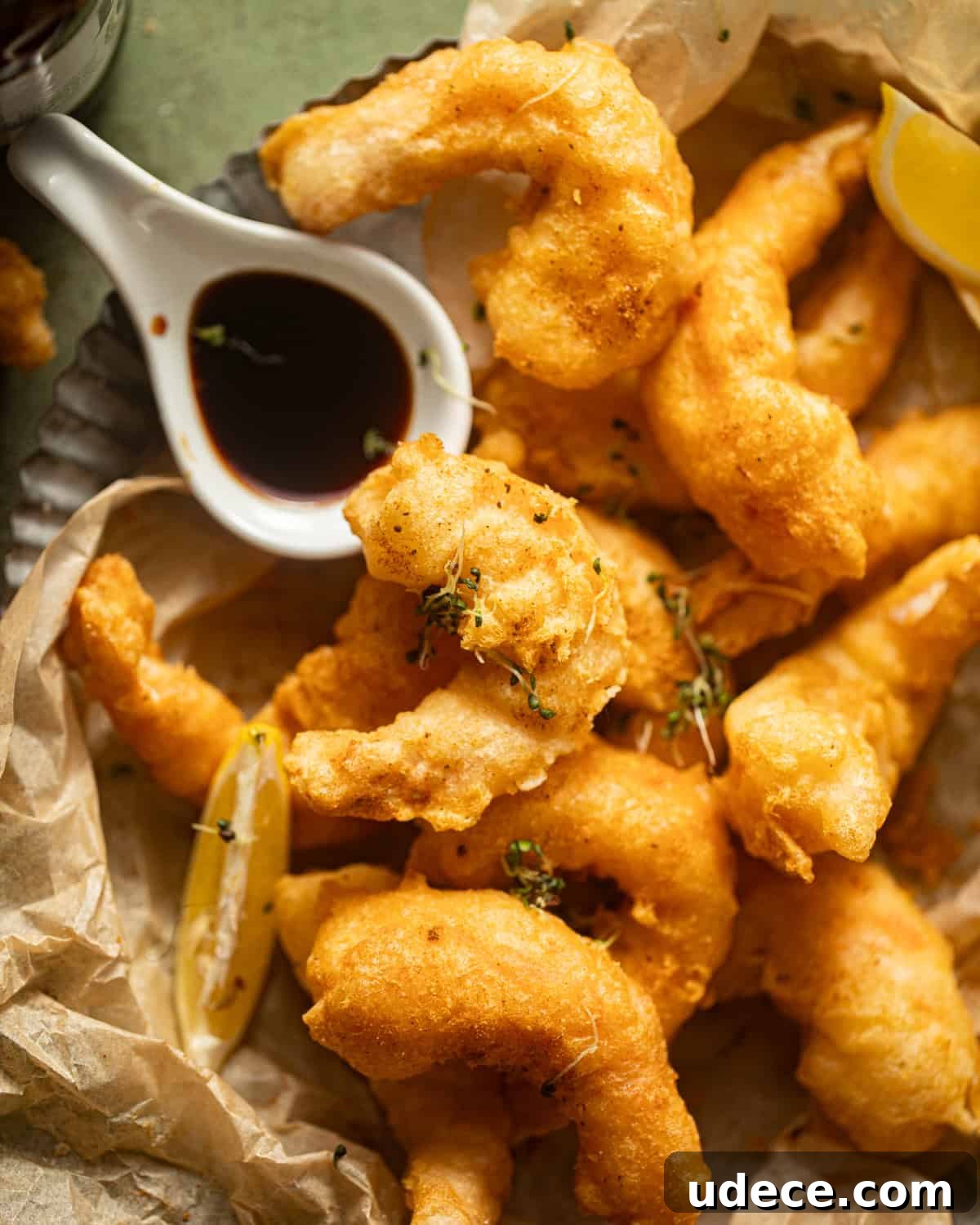 beer battered shrimp on a piece of parchment paper with a lemon wedge.