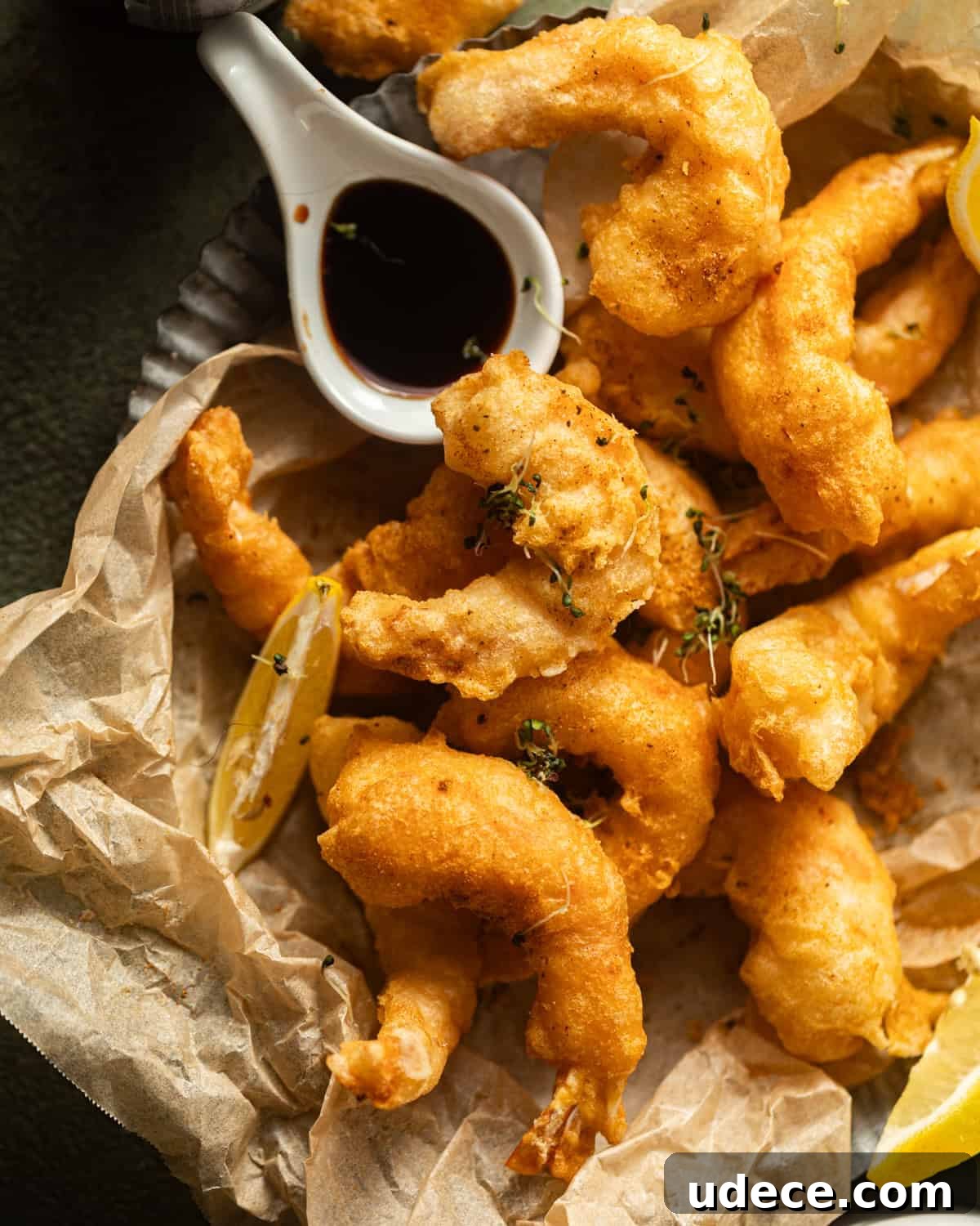 fried shrimp on a silver plate lined with parchment paper with old bay seasoning on top. 