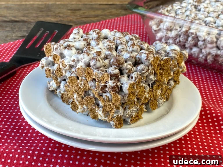 Homemade Cocoa Puffs Cereal Bars Recipe: Crispy Chocolate Treats 2 Thick cocoa puff cereal bar on a stack of white plates with a spatula and the pan full in the background.