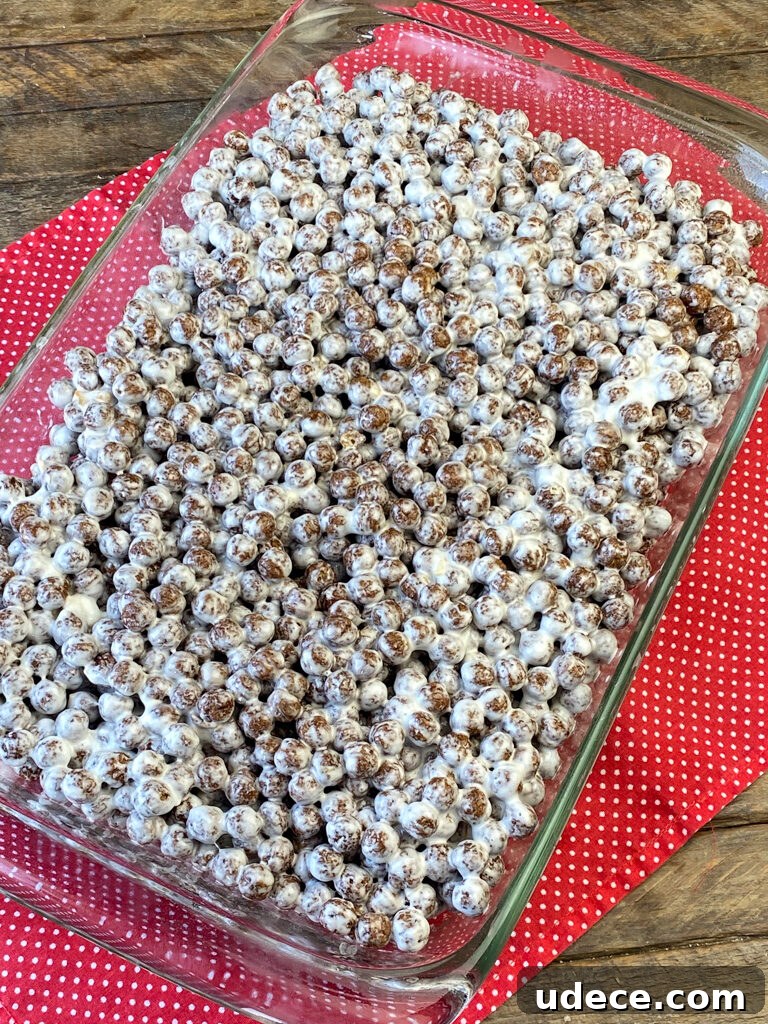 Homemade Cocoa Puffs Cereal Bars Recipe: Crispy Chocolate Treats 6 Pan full of Cocoa Puff cereal bars in a 9 x 13 glass dish on a red and white napkin on a wooden counter top.