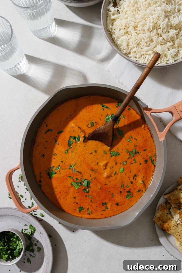 Authentic Butter Chicken Recipe: Tried and Perfected After 20 Tests 2 Top view Butter Chicken in a skillet garnished with cilantro on a dinner table.