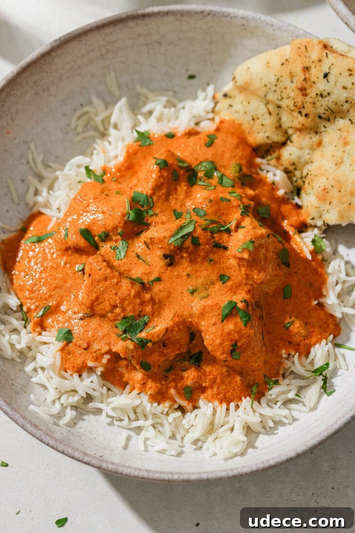 Authentic Butter Chicken Recipe: Tried and Perfected After 20 Tests 3 A bowl of rice topped with Butter Chicken with some naan on the side.