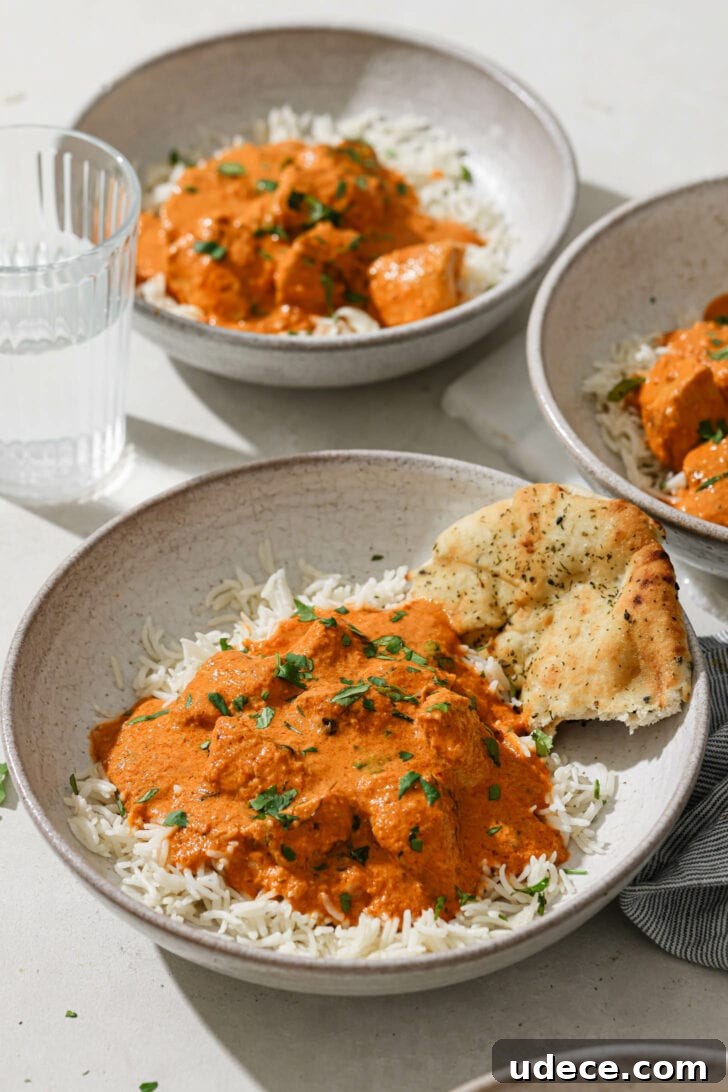 Authentic Butter Chicken Recipe: Tried and Perfected After 20 Tests 4 Bowls of Butter Chicken a top of rice with naan on the side.