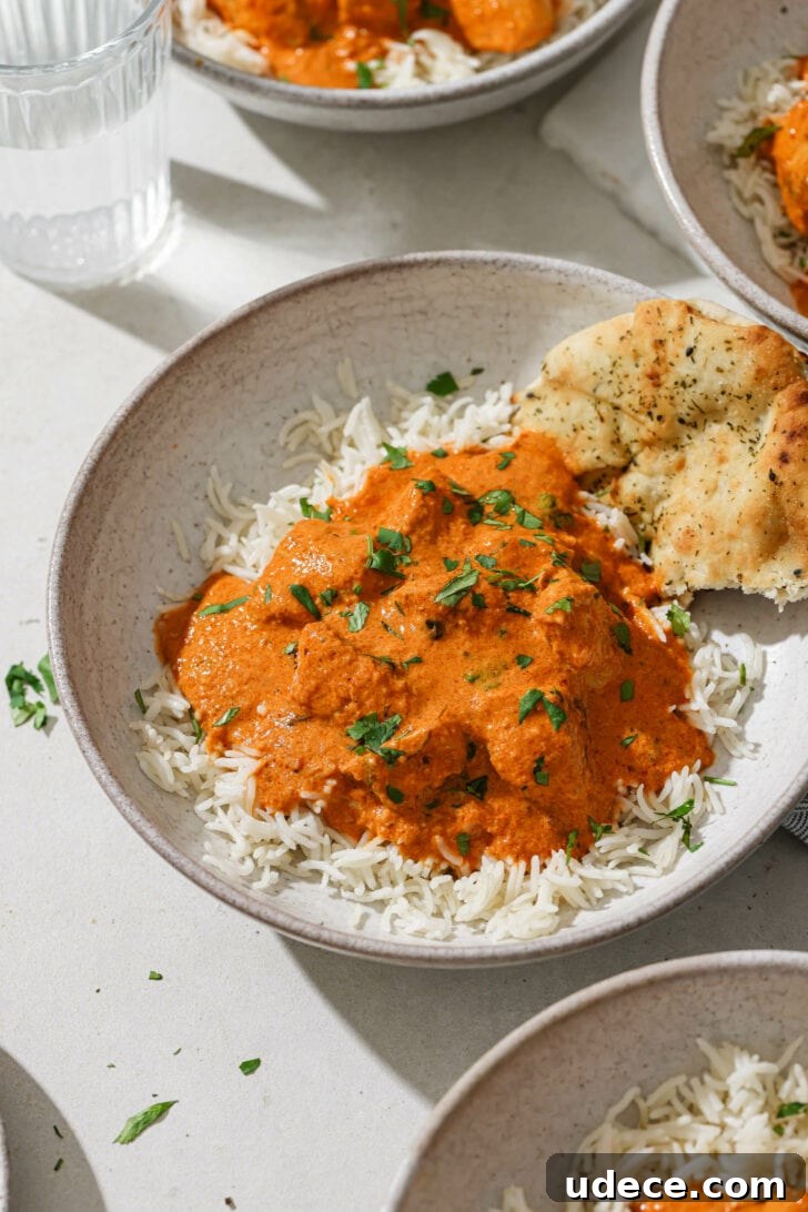 Authentic Butter Chicken Recipe: Tried and Perfected After 20 Tests 36 A bowl of rice topped with Butter Chicken with some naan on the side.