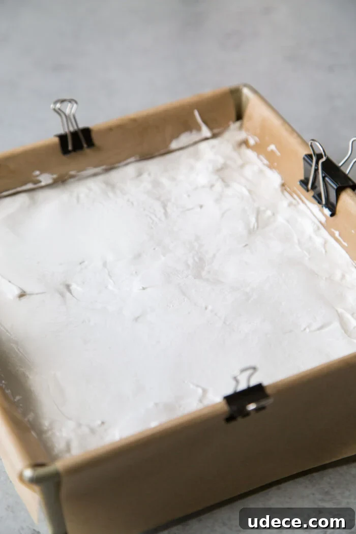 How to Make Fluffy Homemade Marshmallows at Home 13 marshmallow fluff spread in oiled parchment paper lined square pan.