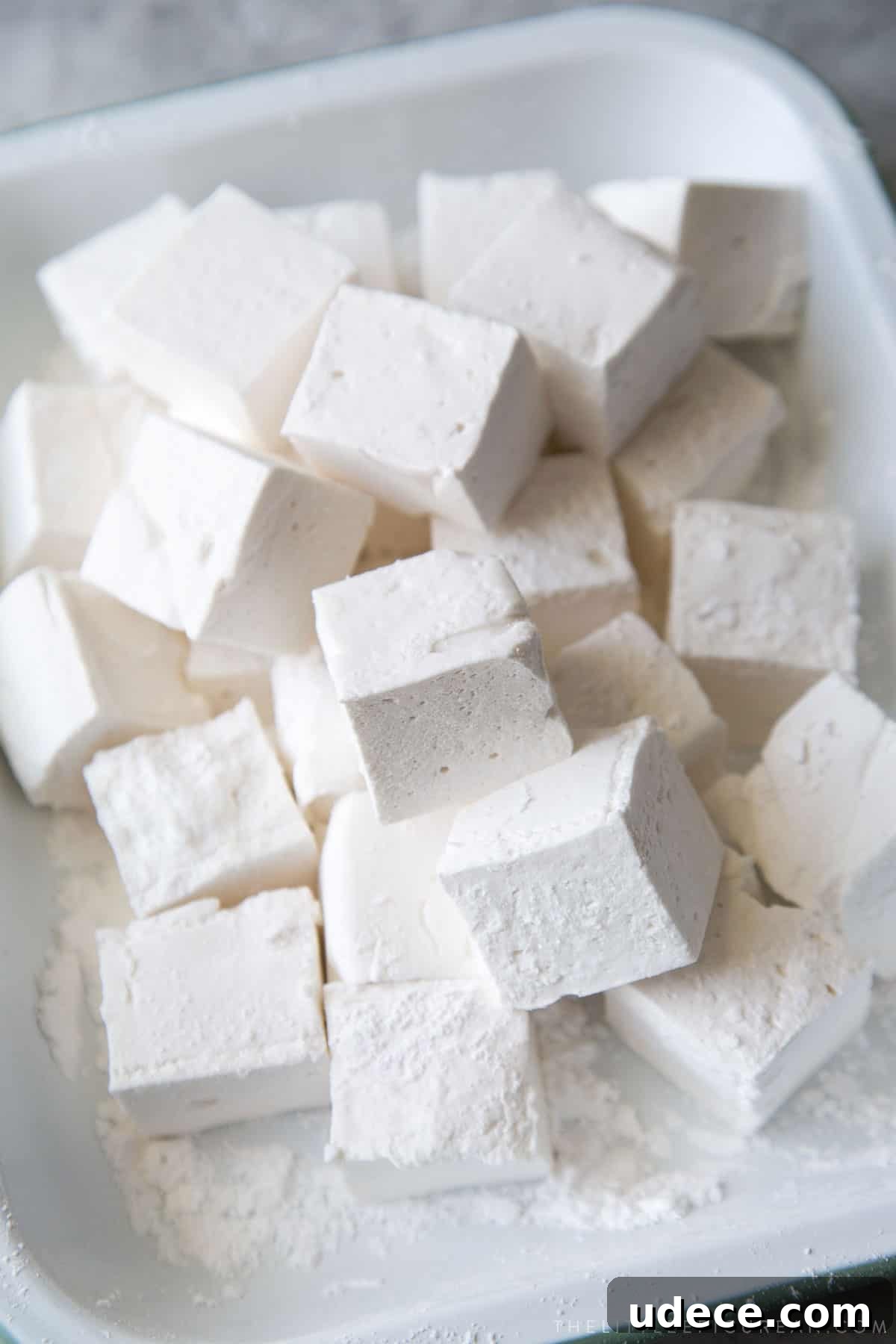How to Make Fluffy Homemade Marshmallows at Home 4 homemade marshmallow squares in a serving platter.