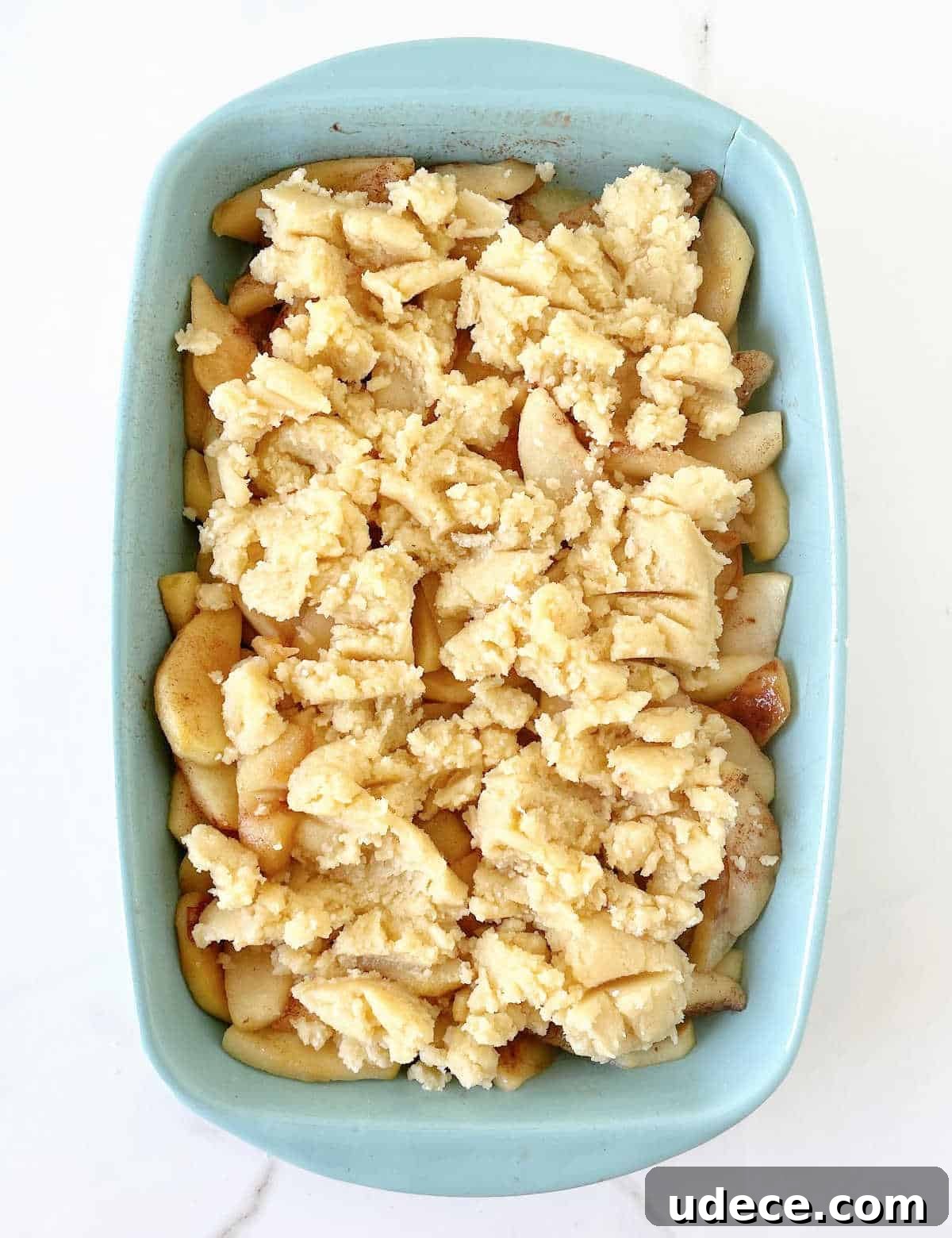 Caramel Apple Dump Cake Recipe — Quick Crowd-Pleasing Dessert 8 Overview of blue rectangular dish with unbaked dump cake, white marble surface.