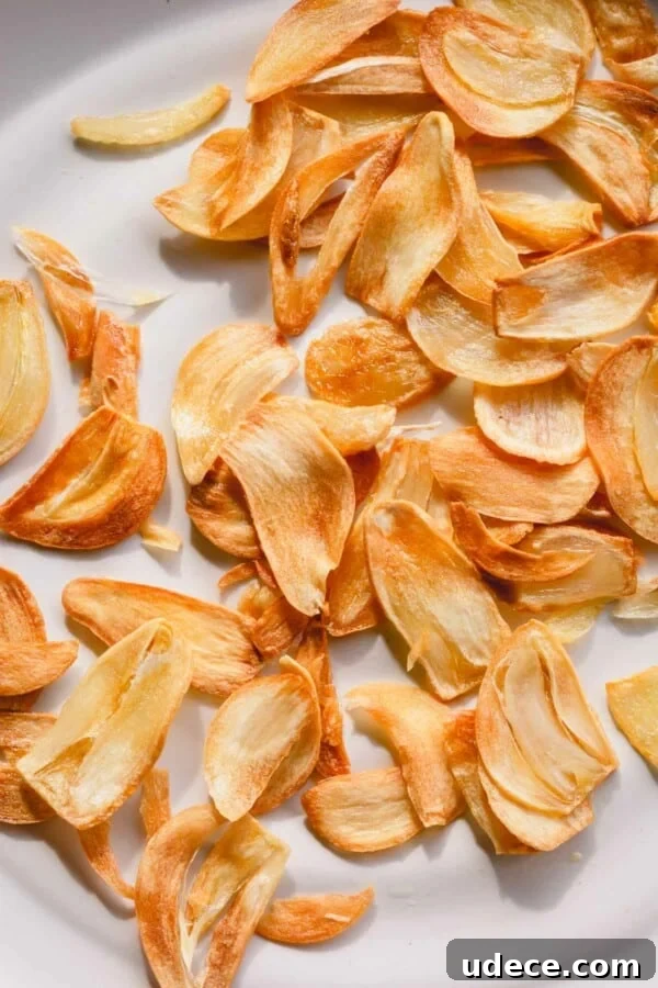 Crispy Garlic Chips Recipe: Homemade Thin Garlic Crisps 2 Golden fried garlic slices on a white plate.