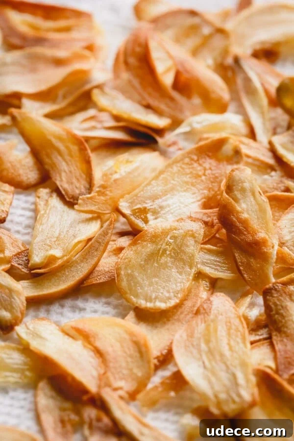 Crispy Garlic Chips Recipe: Homemade Thin Garlic Crisps 5 Upclose shot of fried garlic slices on a paper towel.
