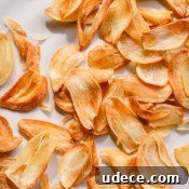 Crispy Garlic Chips Recipe: Homemade Thin Garlic Crisps 8 Golden fried garlic slices on a white plate.