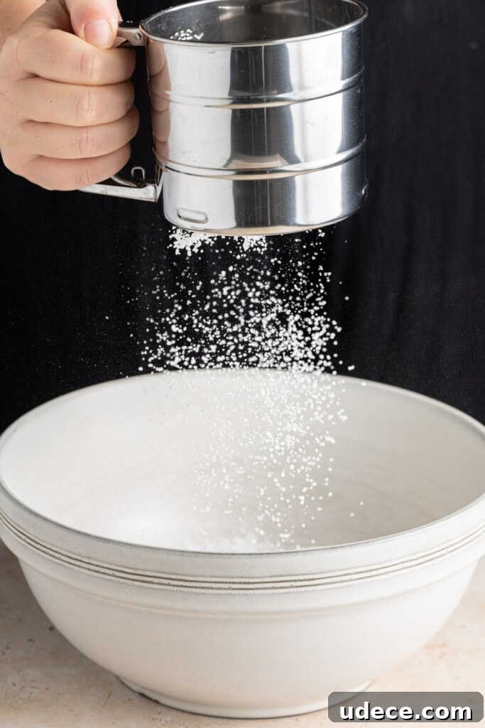 Sifting powdered sugar into cream cheese.