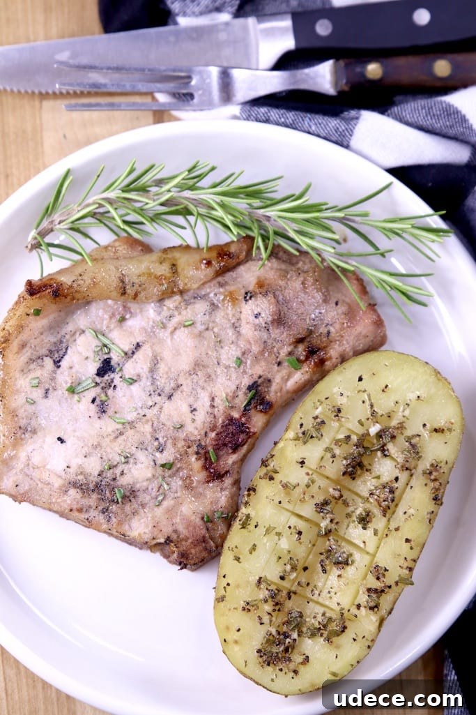 Garlic Butter Baked Potatoes are a simple spin on the classic baked potato Garlic butter potato with pork chop and fresh rosemary on a plate