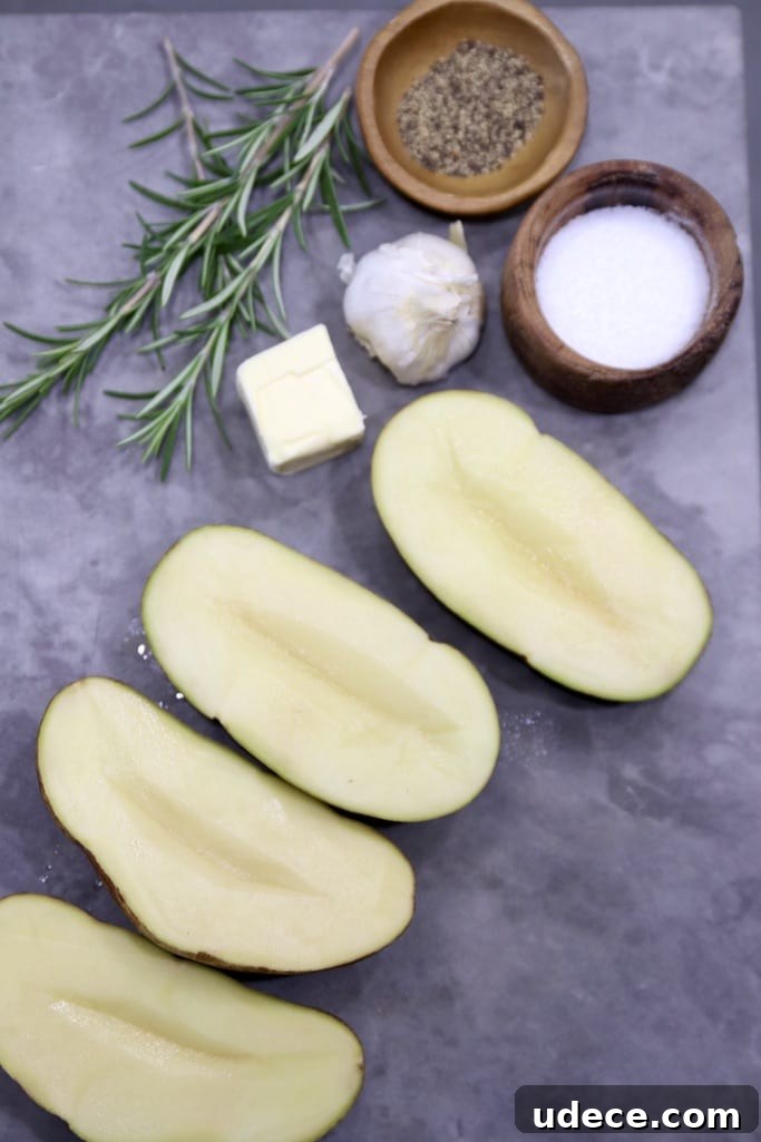 Ingredients for Garlic Butter Baked Potatoes - Grilling Recipe Cutting board with 2 potatoes sliced in half, butter, fresh garlic, rosemary, bowls of salt & pepper