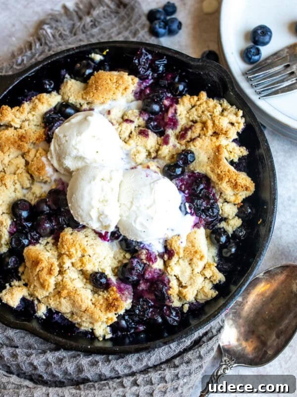 Homemade Blueberry Syrup Recipe for Pancakes and Desserts 8 Black skillet with blueberry cobbler, ice cream and a silver spoon.