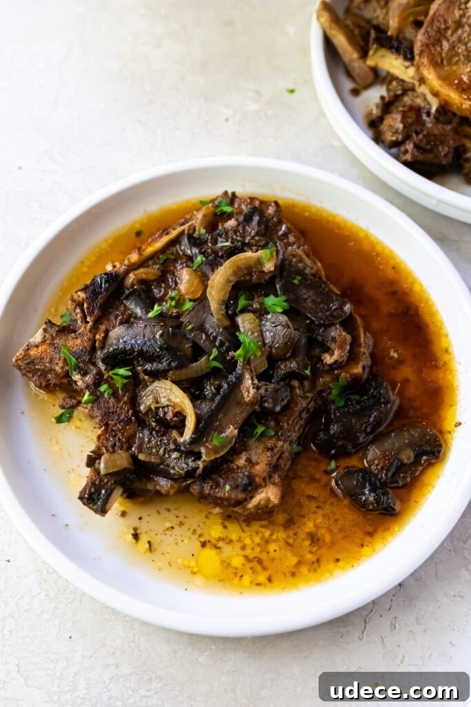 Keto Crockpot Pork Chops Recipe for Tender, Flavorful Meals 2 pork chops with mushrooms and onions on a white plate