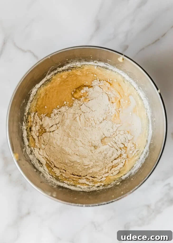High-Altitude Yellow Cupcakes with Rich Chocolate Buttercream 7 A silver bowl of batter and flour on a white counter.
