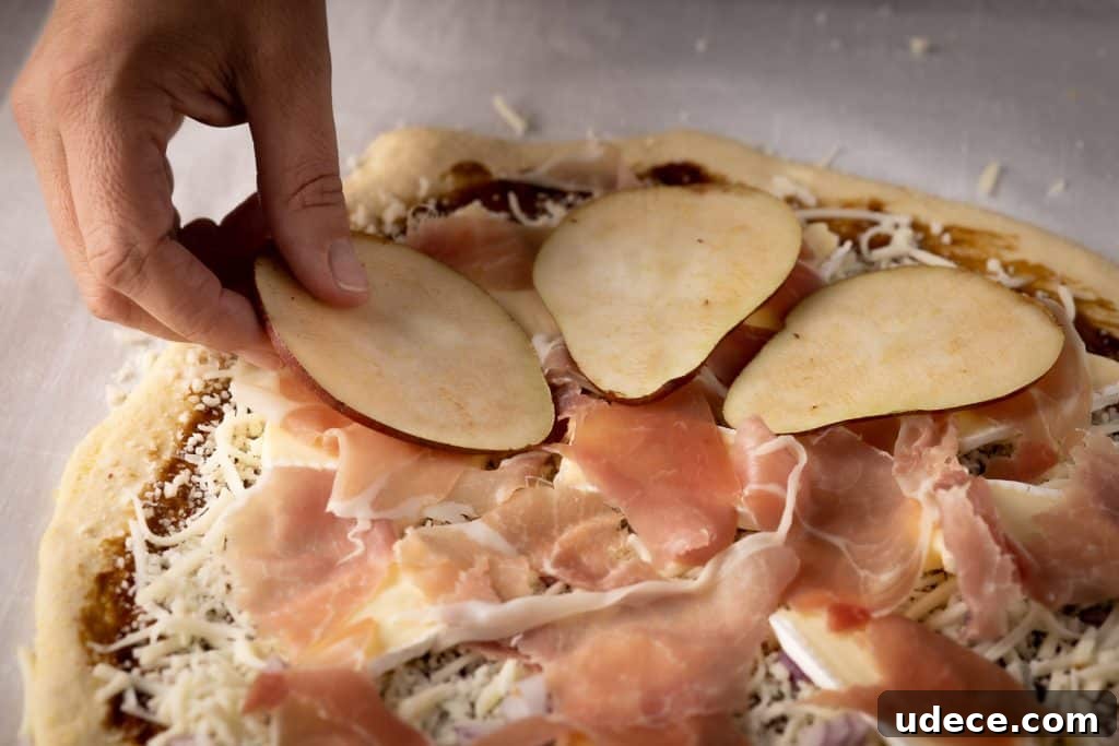Dutch Oven Pizza with Pear, Brie & Prosciutto Recipe 3 Pear slices being added to a deep dish pizza.