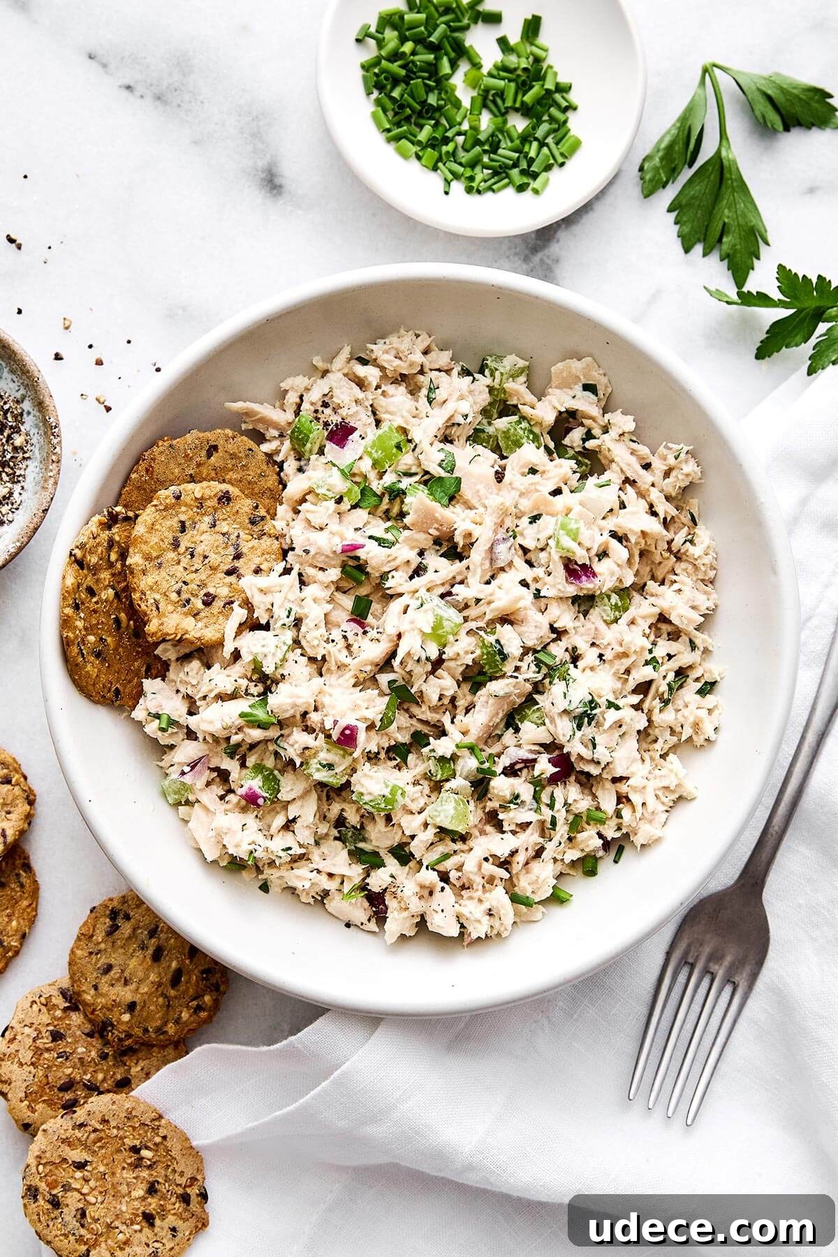 A bowl of tuna salad with crackers.