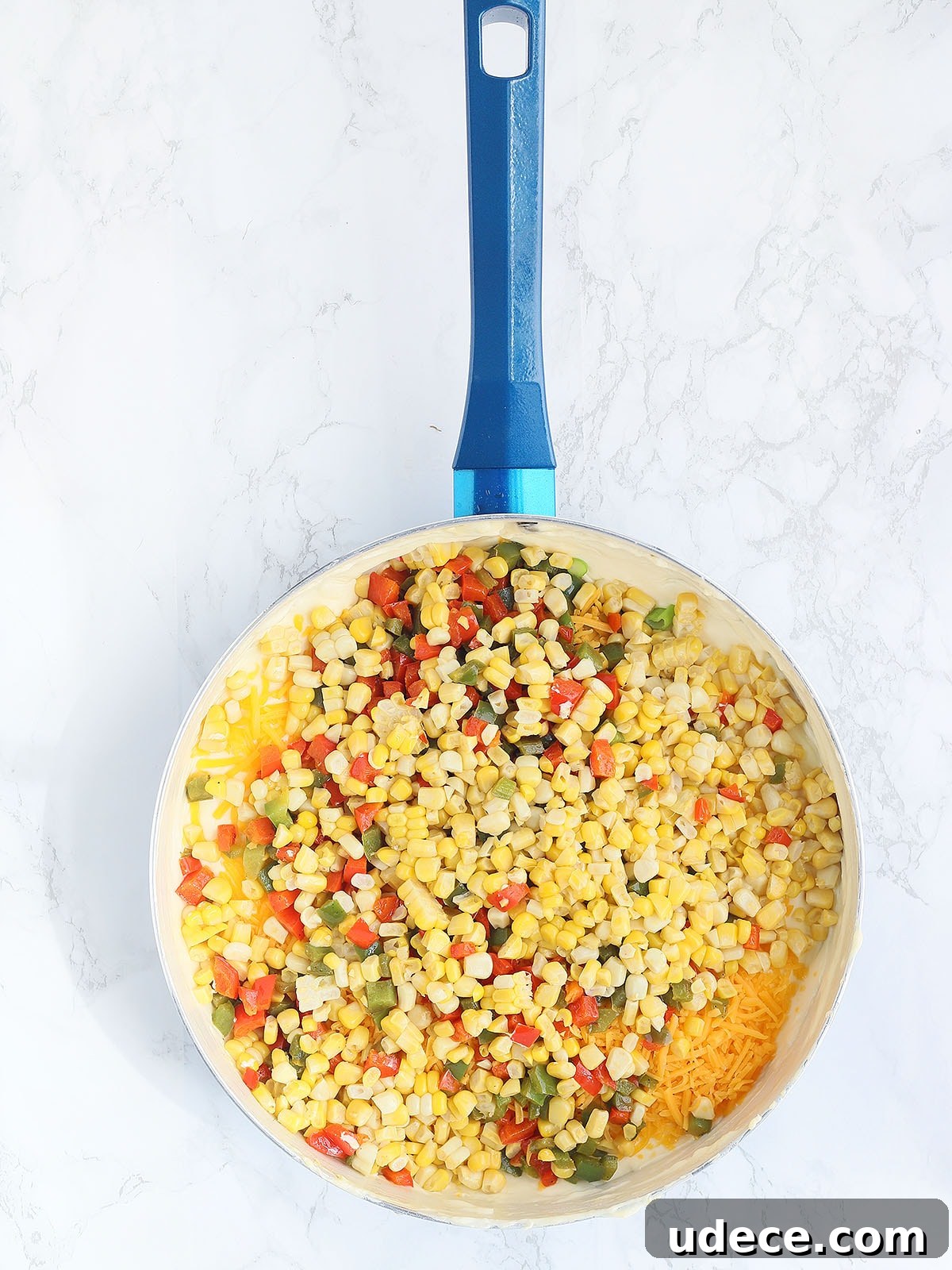 corn, bell pepper, and cheese unmixed in a large blue skillet
