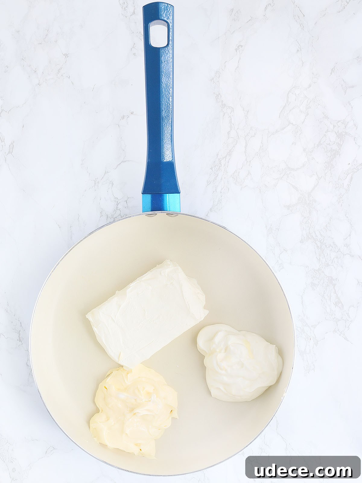 cream cheese, mayonnaise and sour cream unmixed in a large blue skillet