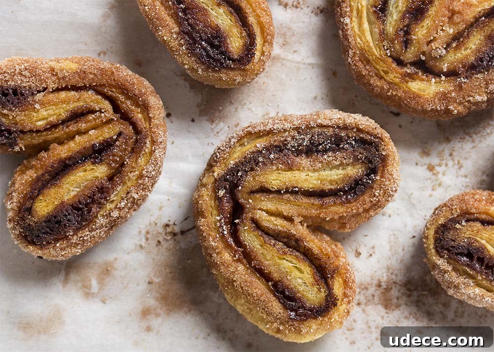 Top view of crispy, caramelized heart shaped palmiers on a baking sheet.
