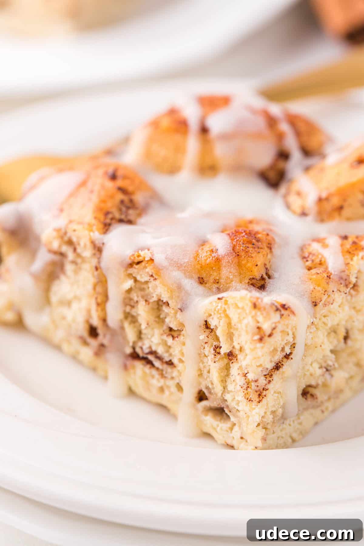 slice of cinnamon roll casserole with icing on white plate