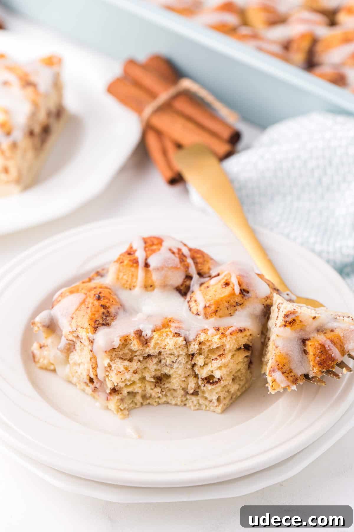 slice of cinnamon roll casserole with icing on white plate