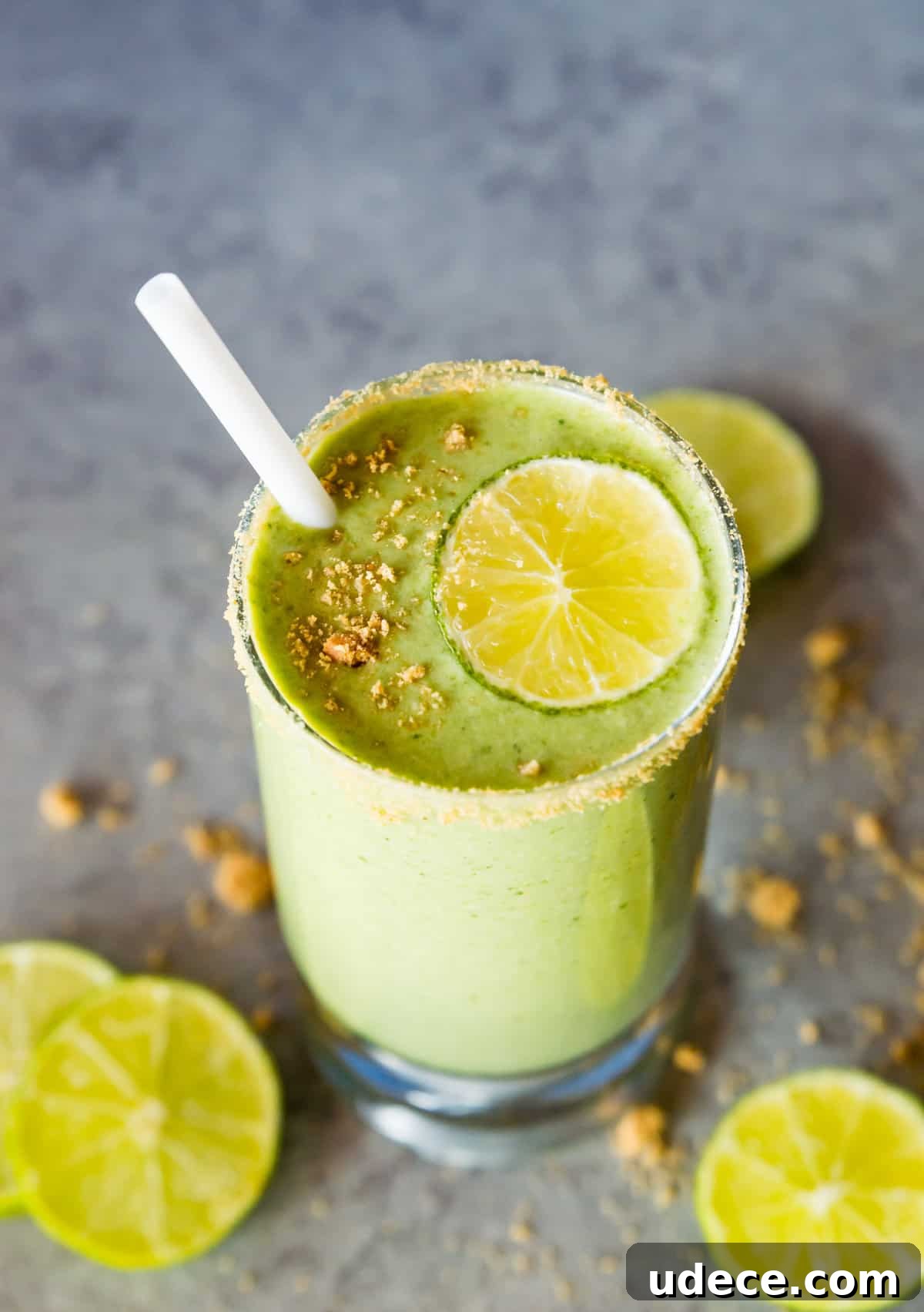 A key lime pie shake in a glass topped with a lime slice and graham cracker crumbs.