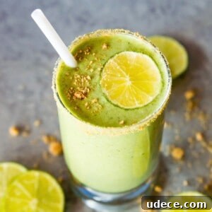 A glass of a key lime pie smoothie topped with a lime slice and crushed graham crackers.