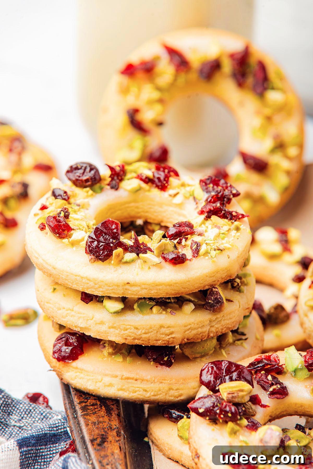 Cranberry Pistachio Holiday Wreath Cookies Recipe 3 A stack of circular cranberry pistachio wreath cookies adorned with dried cranberries and chopped pistachios.