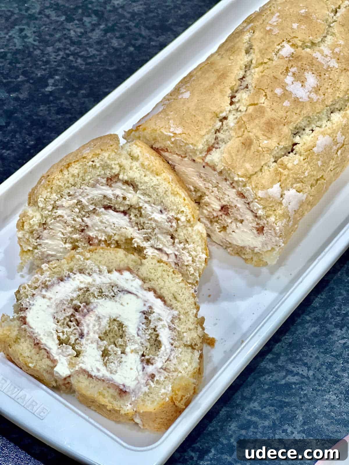 Swiss roll with jam and cream and a slice cut off at the front
