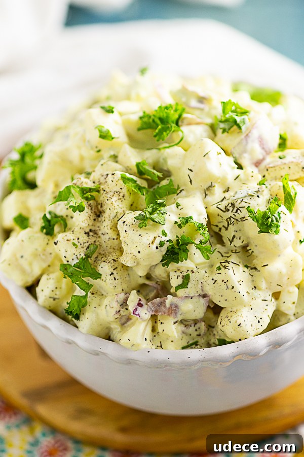 Classic Southern Potato Salad Recipe for Picnics and BBQs 2 Close up overhead view of southern potato salad topped with parsley and dill sitting on a wooden trivet