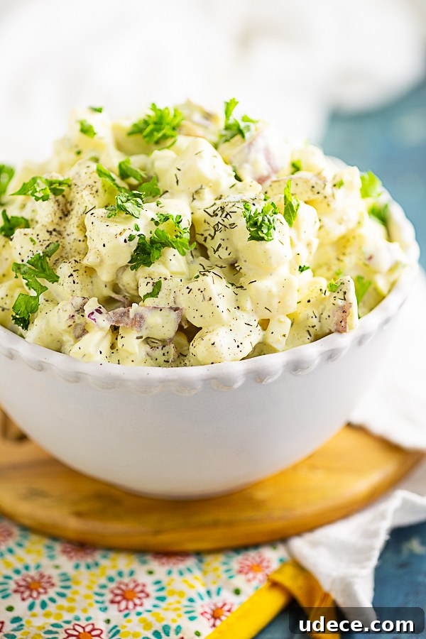 Classic Southern Potato Salad Recipe for Picnics and BBQs 3 Side view of a small bowl of southern potato salad sitting on a wooden trivet and a colorful pot holder