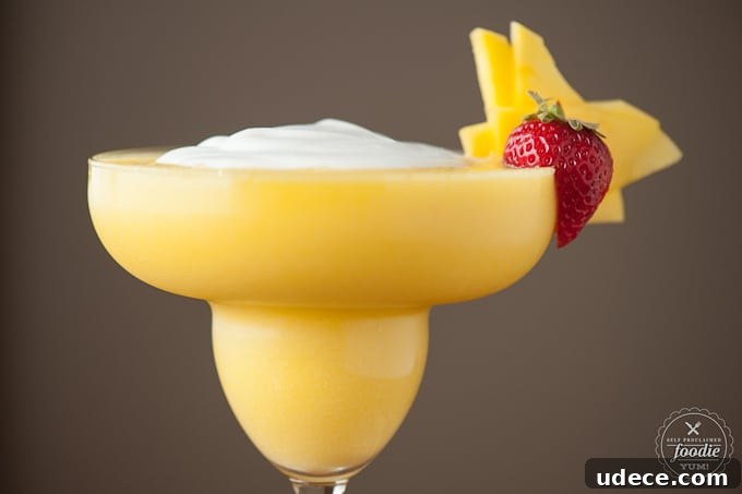 Mango Coconut Daiquiri Recipe: Tropical Cocktail Guide 4 a close up of a blended coconut mango daiquiri with strawberry garnish