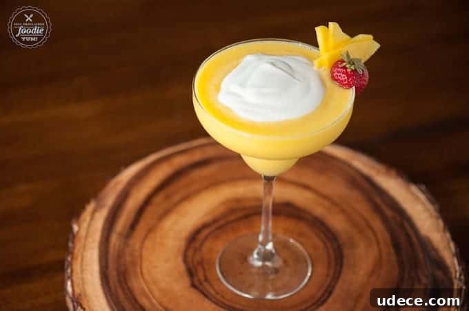Mango Coconut Daiquiri Recipe: Tropical Cocktail Guide 5 A margarita glass with a Mango Coconut daiquiri with a cream topping and garnish