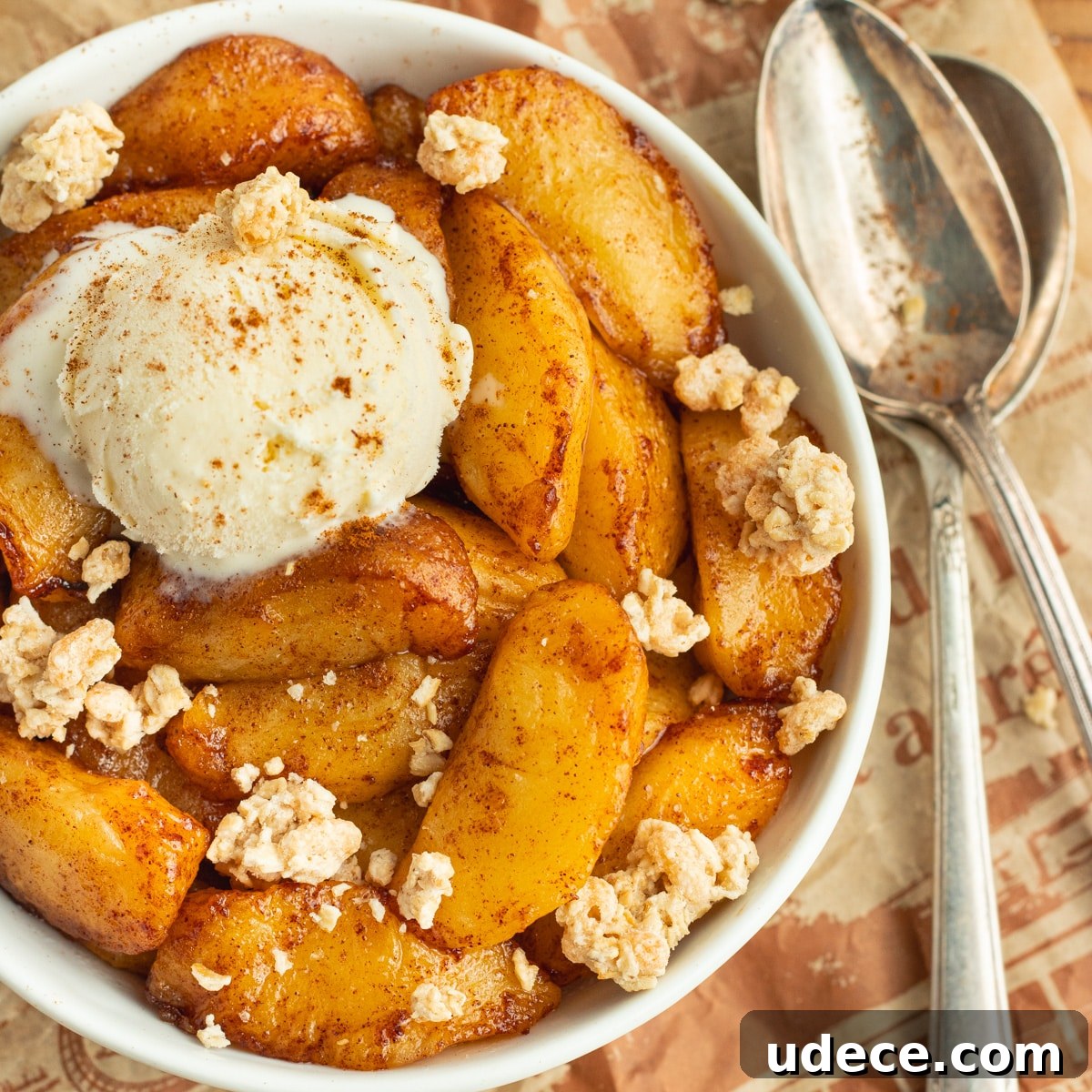 This is a picture of a bowl with cooked apples with ice cream and granola.