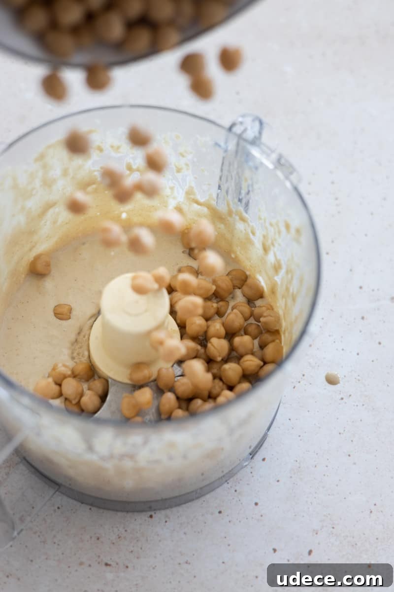 Adding chickpeas to food processor.