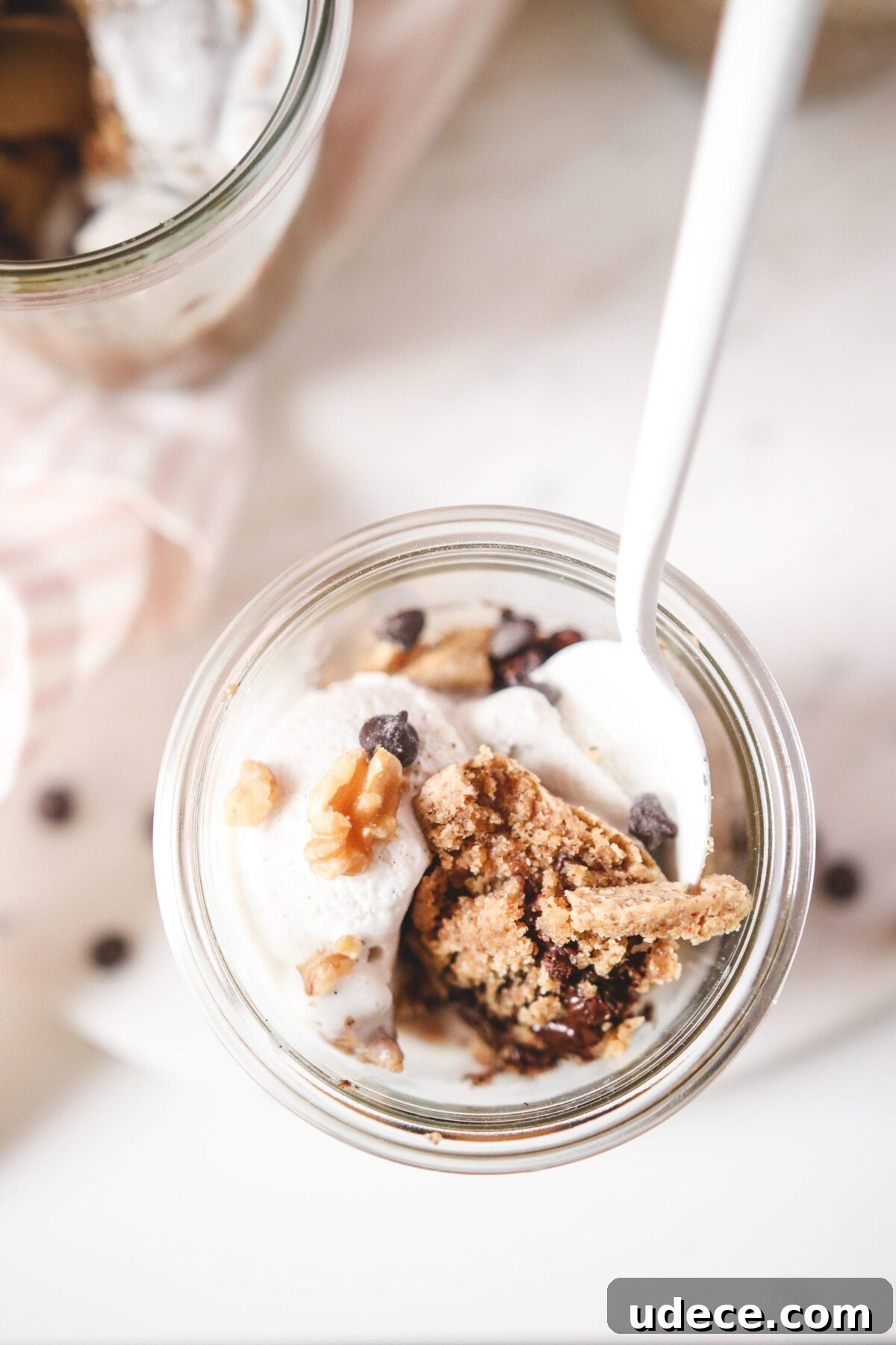 an overhead shot of chocolate chip cookies jars with a white spoon resting on top