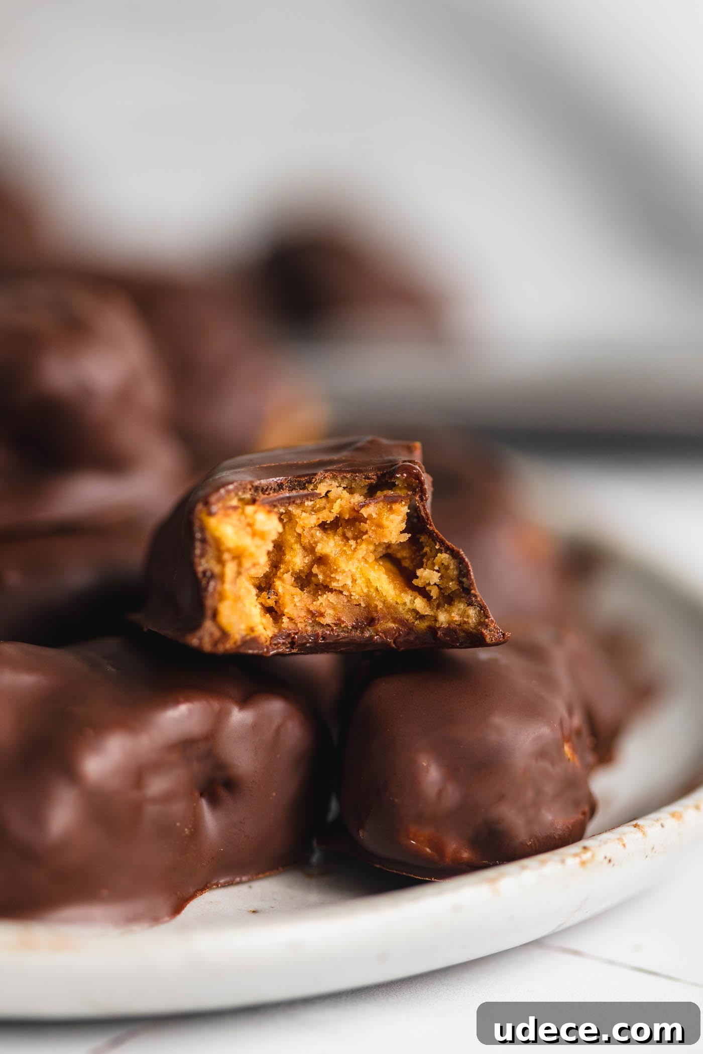 Homemade Butterfinger Candy Recipe Without Candy Corn 2 A plate of homemade butterfinger candy with one sitting on top with a bite out of it so you can see the crunchy texture inside.