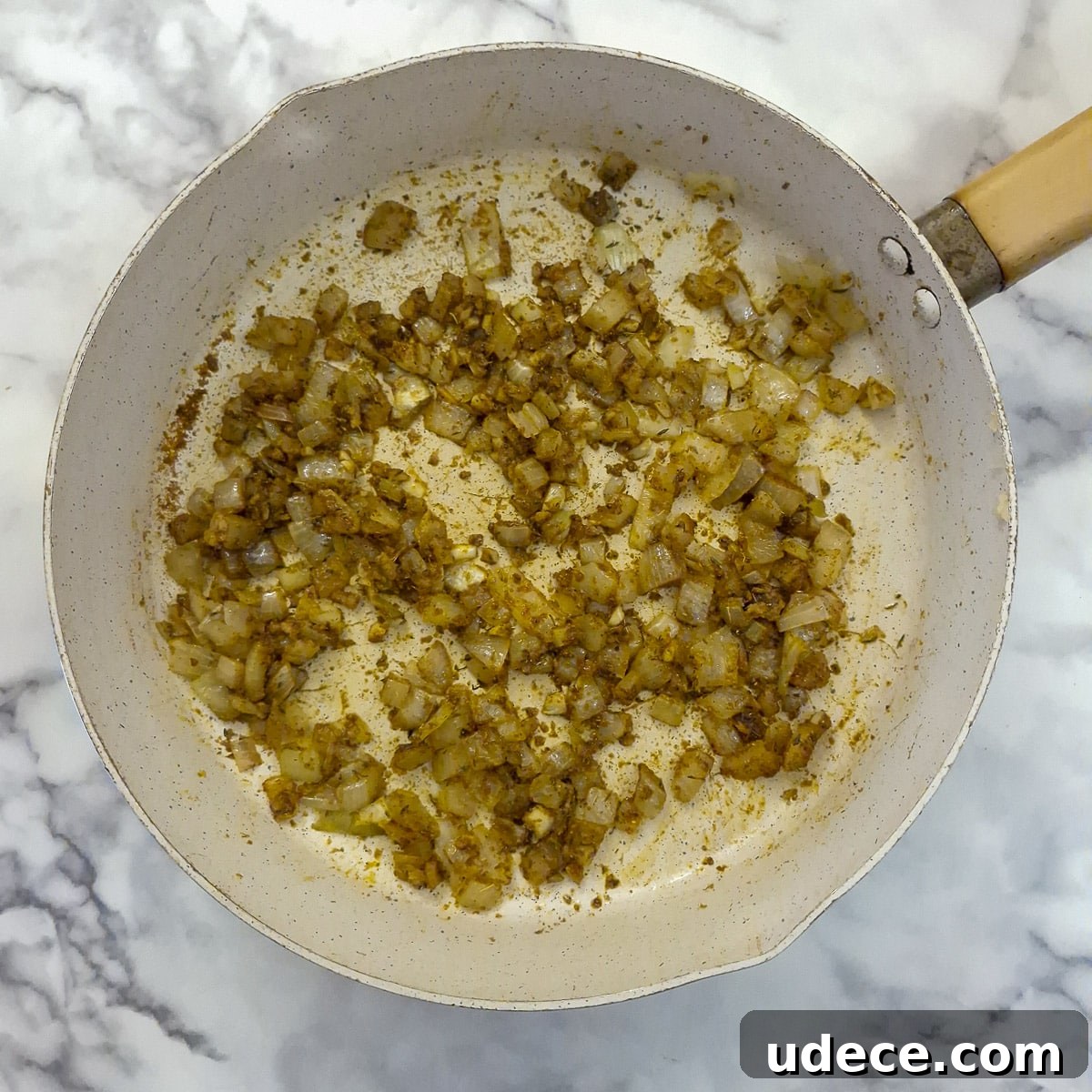 Chakalaka Recipe: Authentic South African Spicy Vegetable Relish 6 Step 2, spices mixed with fried onions in a pan.