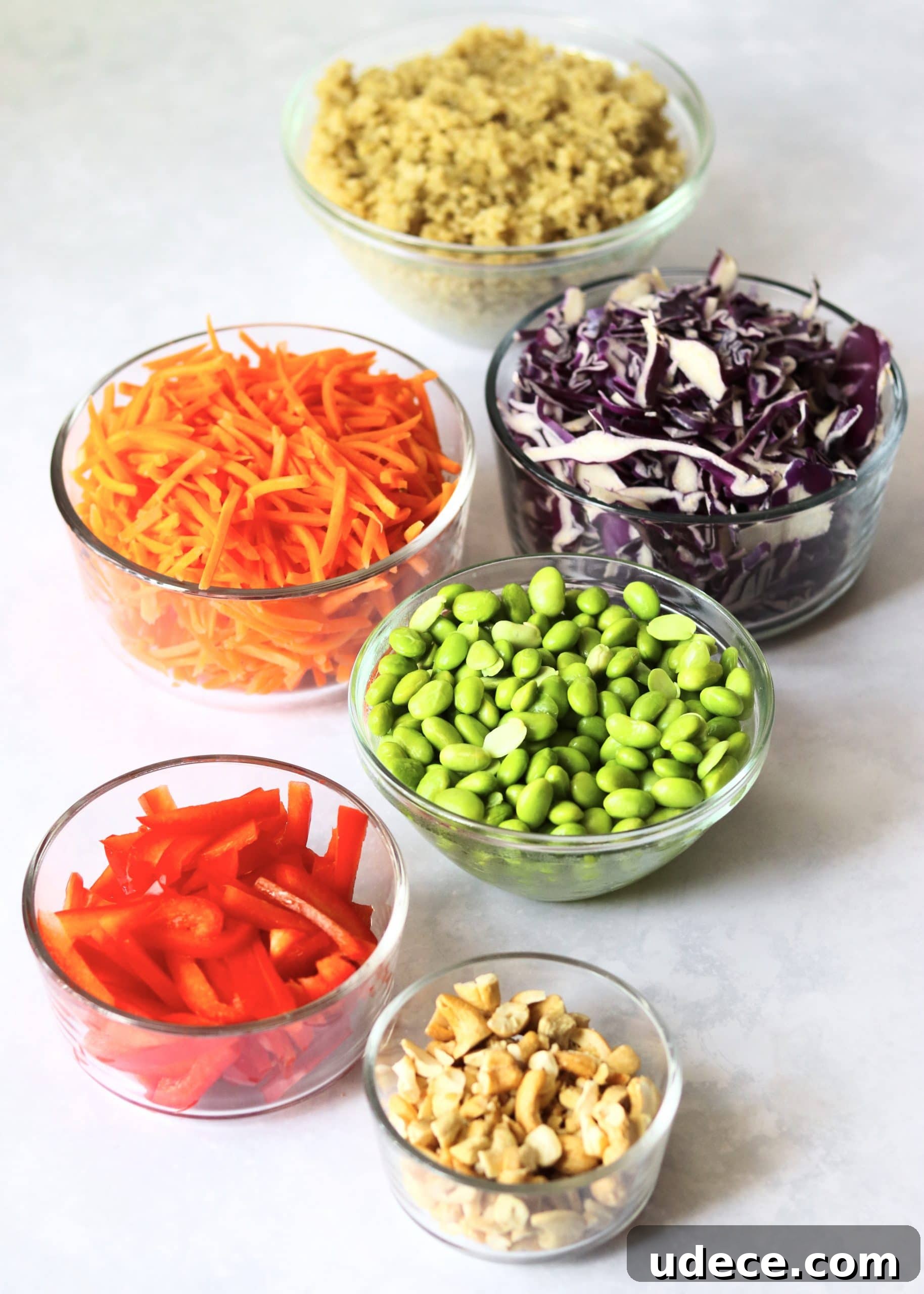 Thai Quinoa Mason Jar Salad Recipes for Meal Prep 3 Quinoa, shredded cabbage, shredded carrots, edamame, bell pepper, and cashews in glass bowls