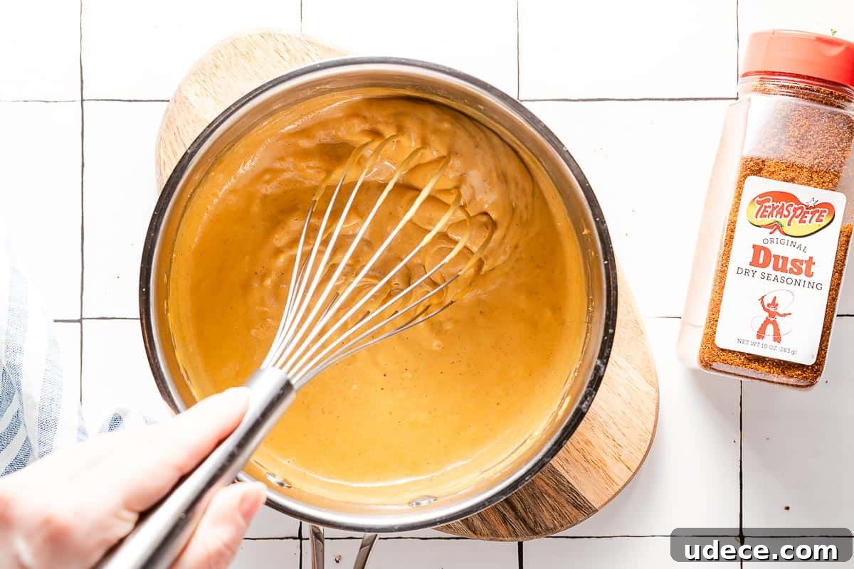 Spicy Queso Chicken Nachos Recipe for Game Night 5 queso in pot being whisked