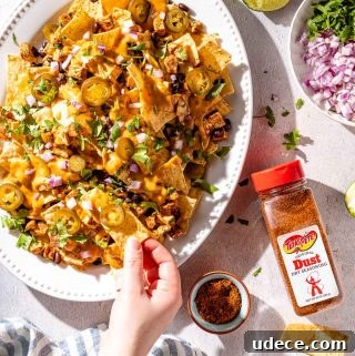 Spicy Queso Chicken Nachos Recipe for Game Night 10 hand taking nacho from platter