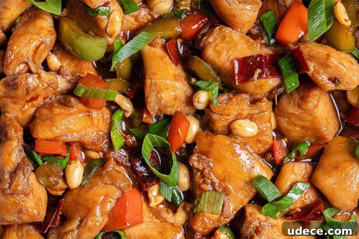 Close up image of Kung Pao Chicken in a sticky Kung Pao sauce with green and red chopped vegetables picked in with chicken pieces.