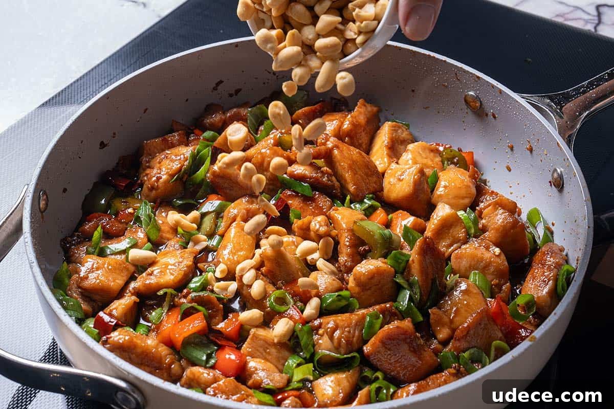 garlic, ginger, chili diced peppers (capsicums) and Sichuan peppercorns and chicken with peanuts being poured over