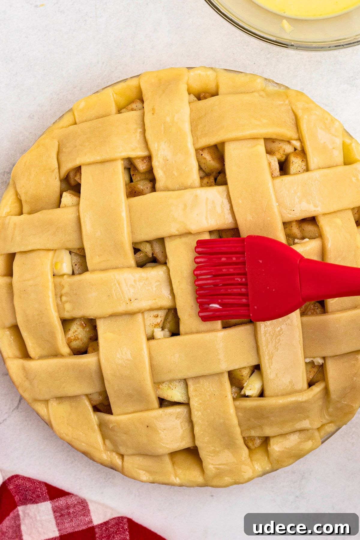 Classic Homemade Apple Pie Recipe for Perfect Crust and Filling 8 Uncooked apple pie with egg wash being brushed on top with a red pastry brush.