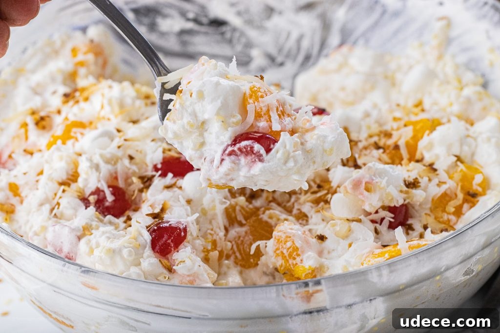 Refreshing Frog Eye Salad Recipe with Pineapple & Whipped Cream 5 spoon scooping out a spoonful of fruit salad