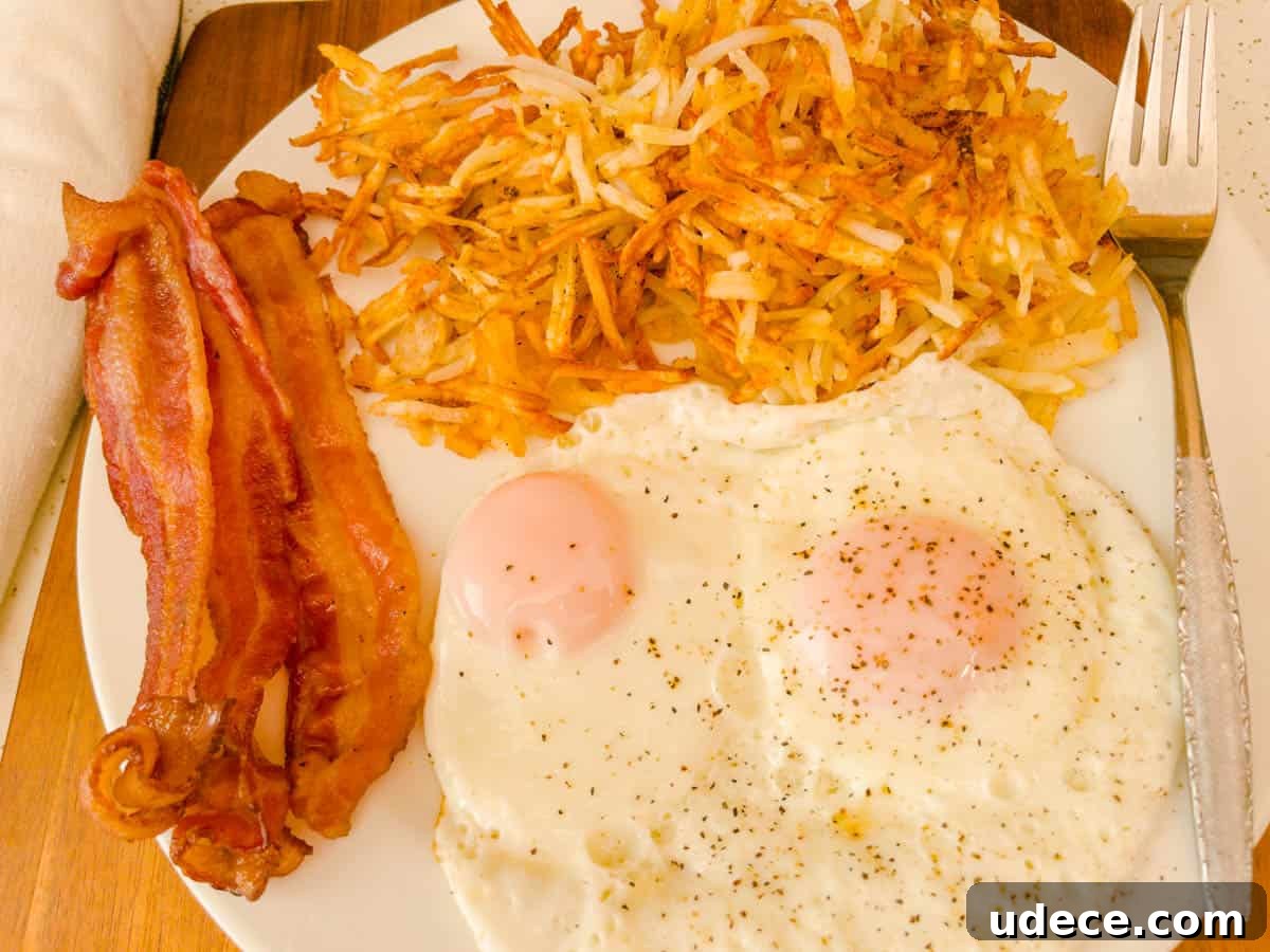 Crispy Air Fryer Hash Browns Ready in 15 Minutes 2 Bacon over easy eggs on a plate with hash browns